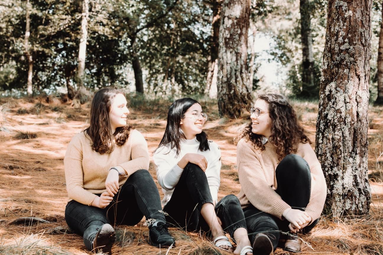 Photo of three friends chatting in the forest