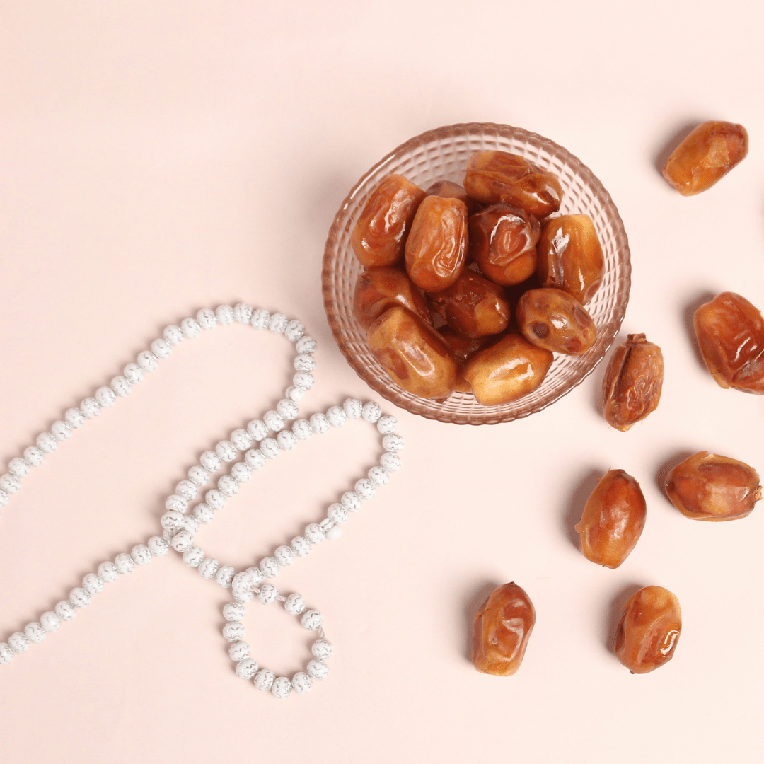 Dates and prayer beads on pink background