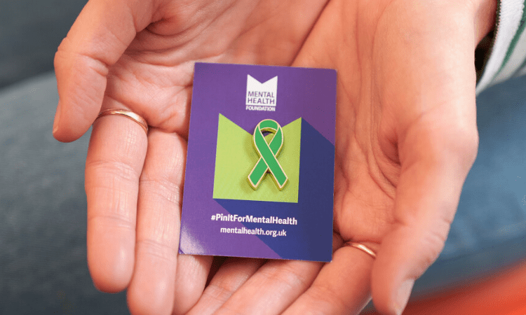 Someone holding a green ribbon pin badge
