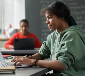 A teenage girl uses a laptop in her classroom