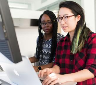 Two women working on a computer together
