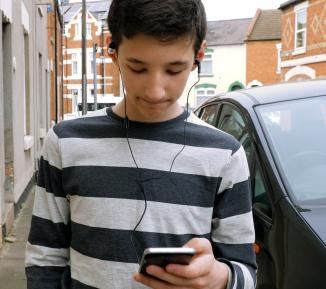 boy with phone alone on street.