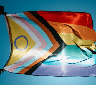 Pride flag blowing in the breeze with sun behind
