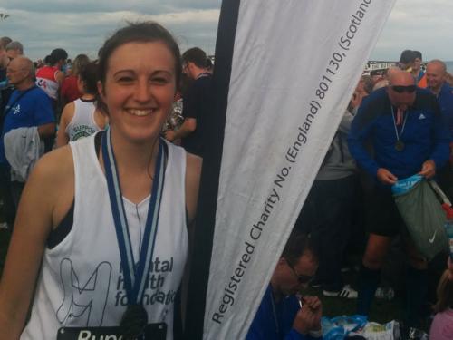 Female runner with medal posing with banner