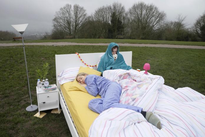 Image of a couple asleep in bed, one fast asleep and the other under a big blanket