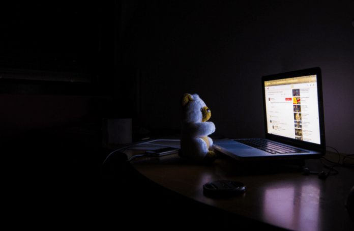 Image of a teddy bear looking at a laptop