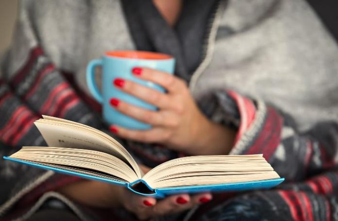 Woman reading a book with a cup of tea