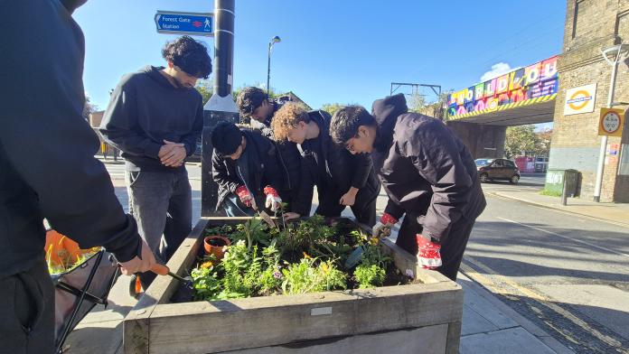 The image features members of young people gathered together gardening outside of Forest Gate station in London. They are members of Ashok's Vision International who won the Positive Mental Health Image Library competition.