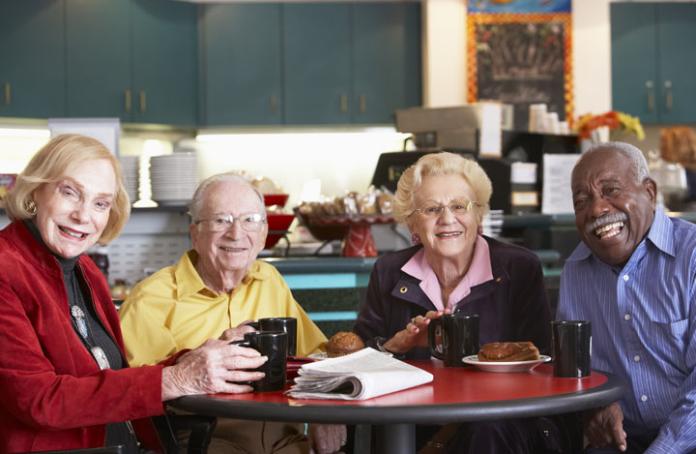 A group of elderly people sat together and smiling