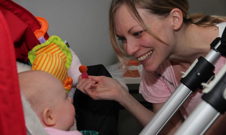 Photo of a mum playing with her baby in their buggy