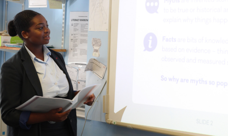 A student working at the whiteboard in a classroom, as part of the Peer Education Project
