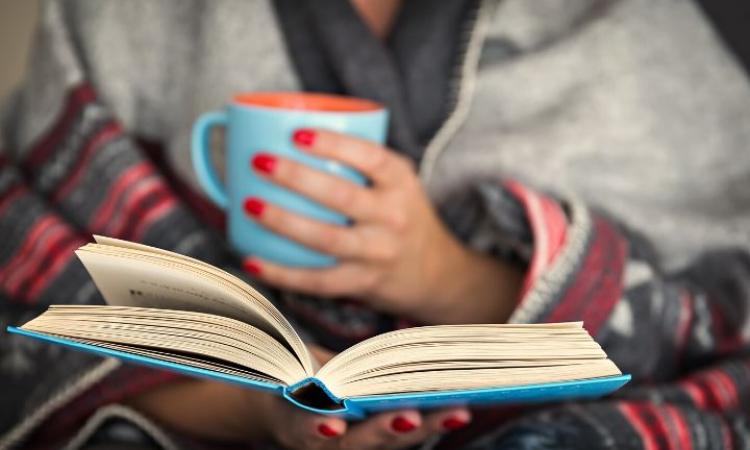 Woman reading a book with a cup of tea