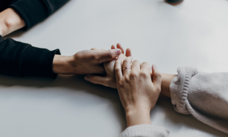 Two people holding hands over a table