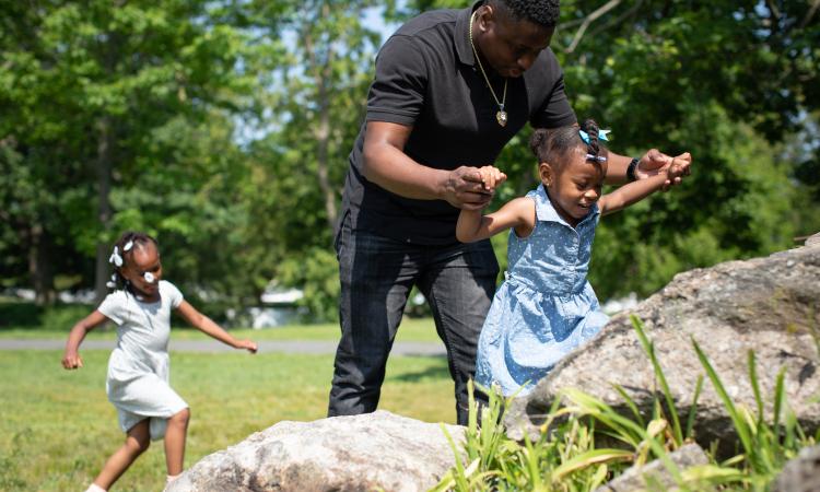 Photo of a father and his two daughters playing in nature