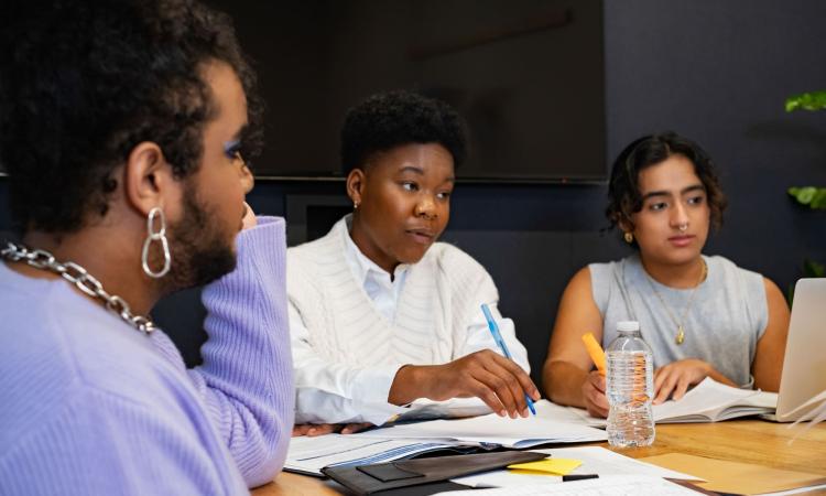 Photo of three people working around a table