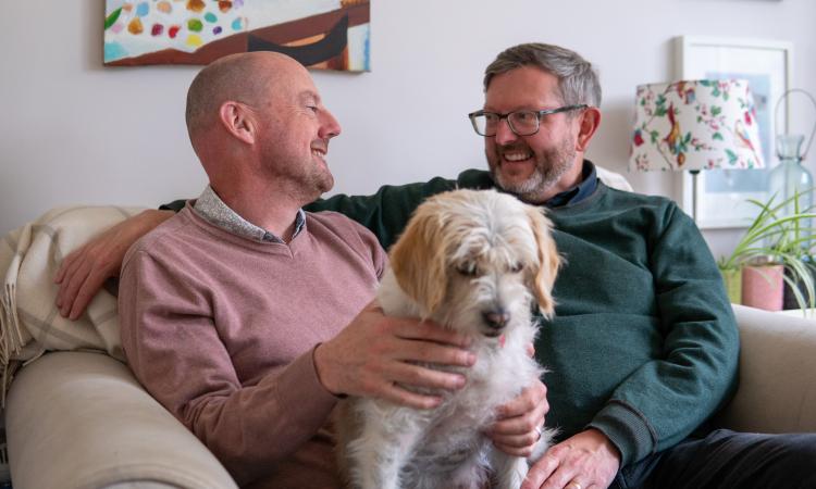 Photo of an older gay couple sat with their dog