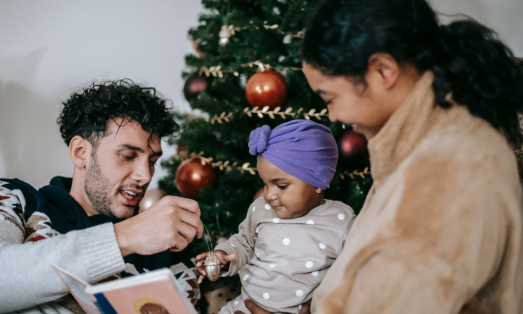 A family with a young child stood by a Christmas tree. 