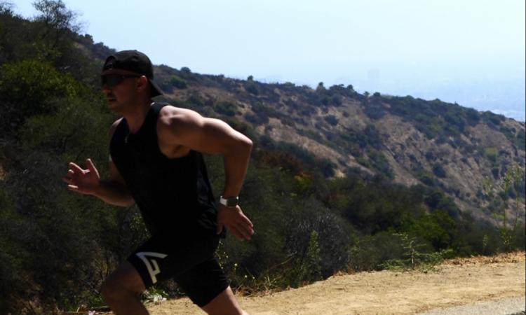 A man running along a road in the sunshine