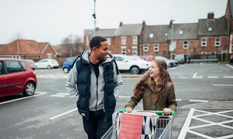 Man and woman with shopping trolley in car park