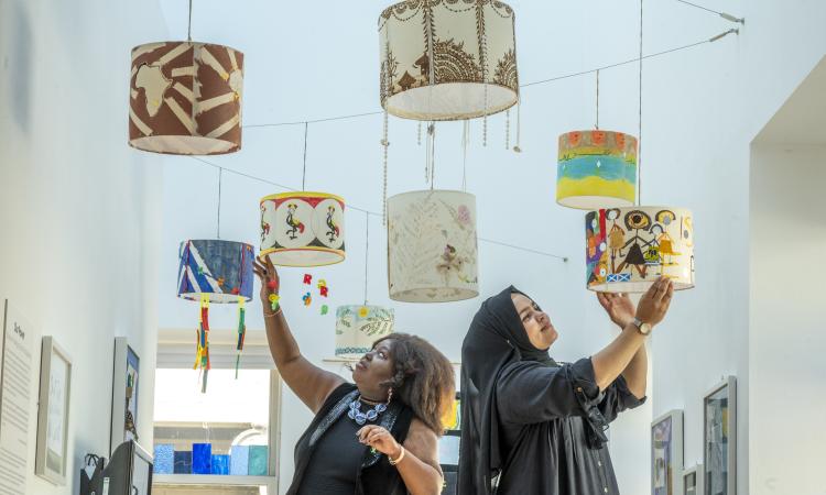 Two women hang decorative lamps