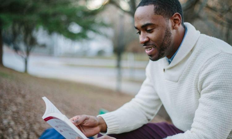 Man in White Sweater Reading Book