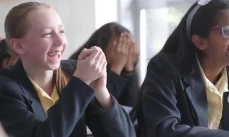 Two schoolgirls laughing in classroom
