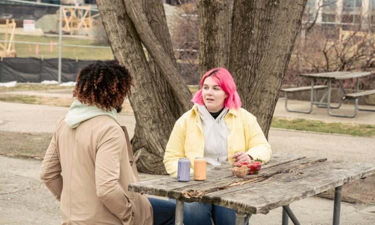 Two people talking at a park bench