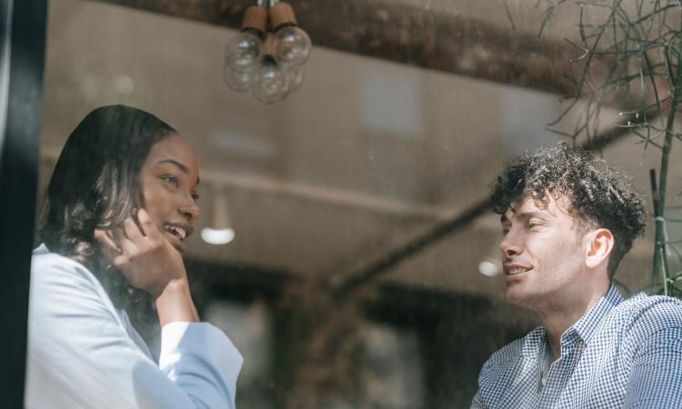 Two people talking seen through a window