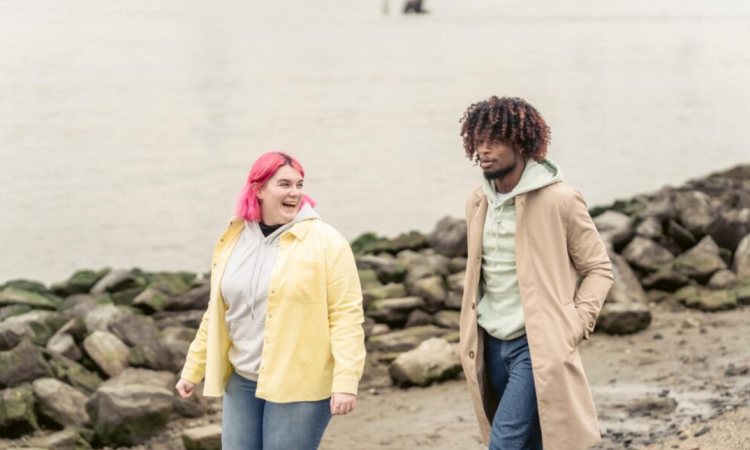 A young man and woman walk along a beach path talking together
