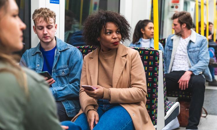A White man and a Black women are sitting on an underground train