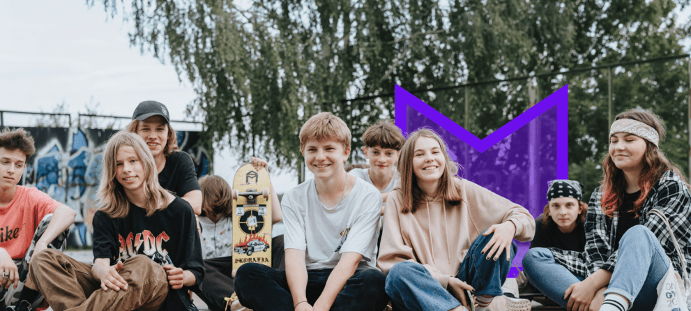 A group of young people sitting on the ground in a skate park