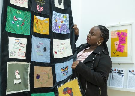 Mary hangs a textiles artwork on the wall at the Our Power exhibition