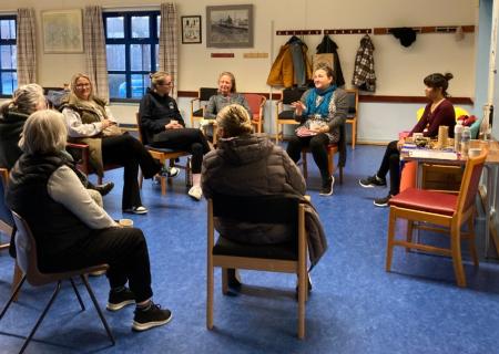 A circle of women sat indoors talking