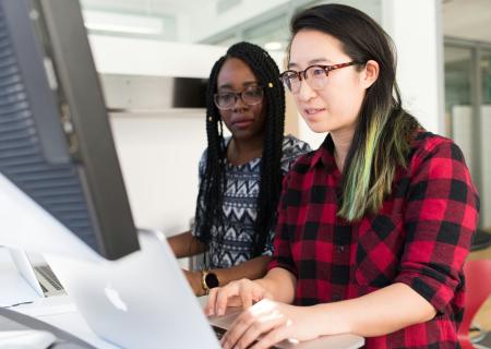 Two women working on a computer together