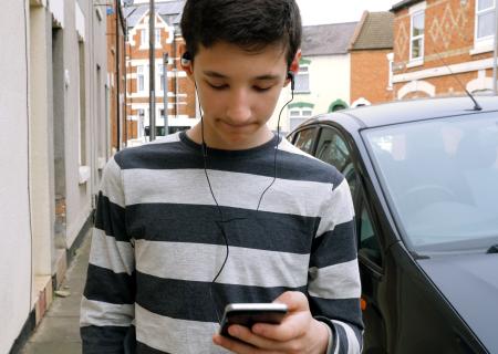 boy with phone alone on street.