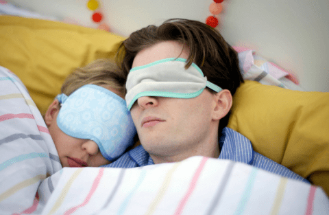 Image of a couple asleep in bed, with eye masks on