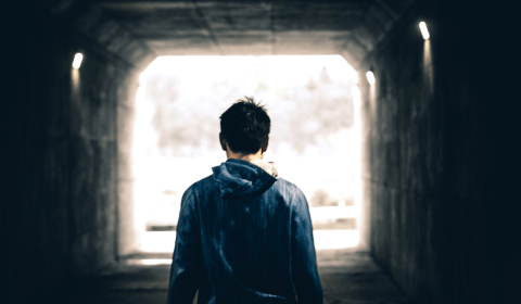 A man walking towards the light at the end of a tunnel