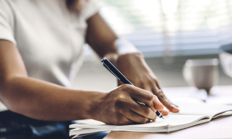 Hands of a person writing on a notepad